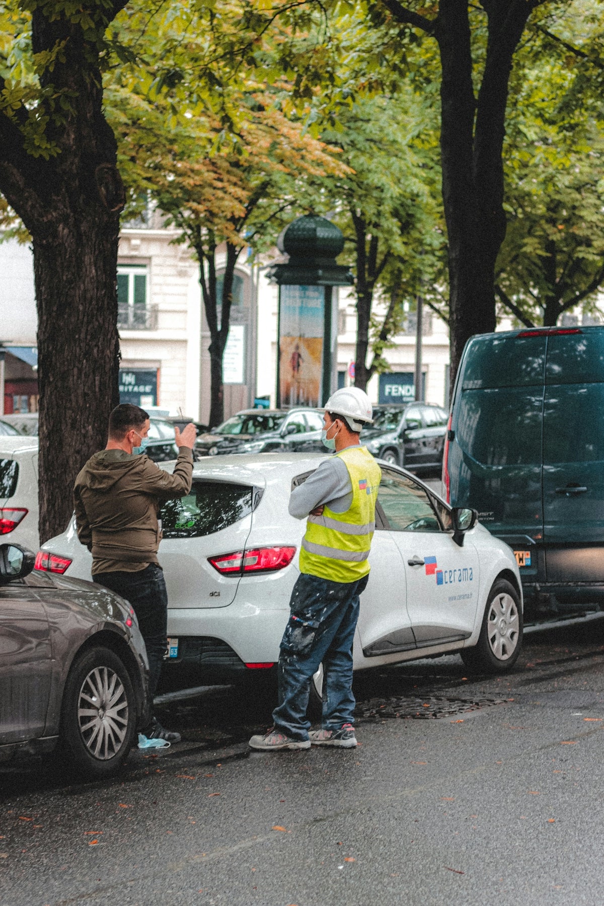 man in brown jacket standing beside white car during daytime