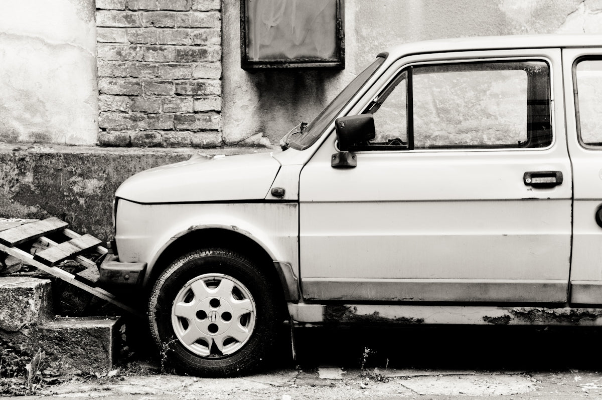 white car parked beside brown brick wall