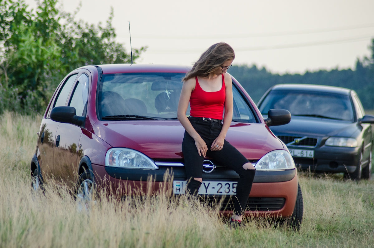 woman in black tank top standing beside red honda car during daytime