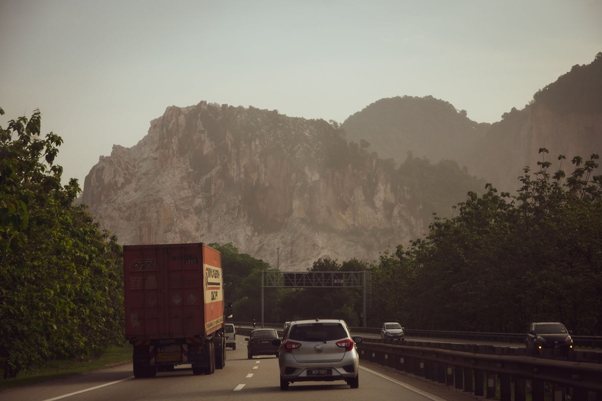 a car driving down a road with a mountain in the background