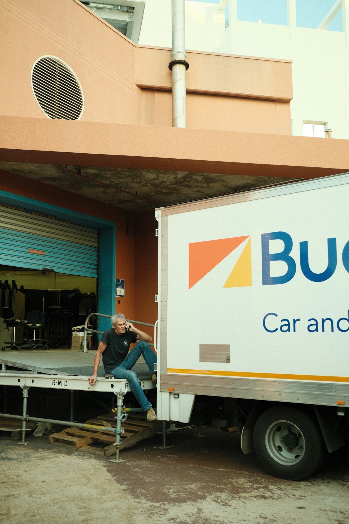 a man sitting on the back of a truck in front of a building