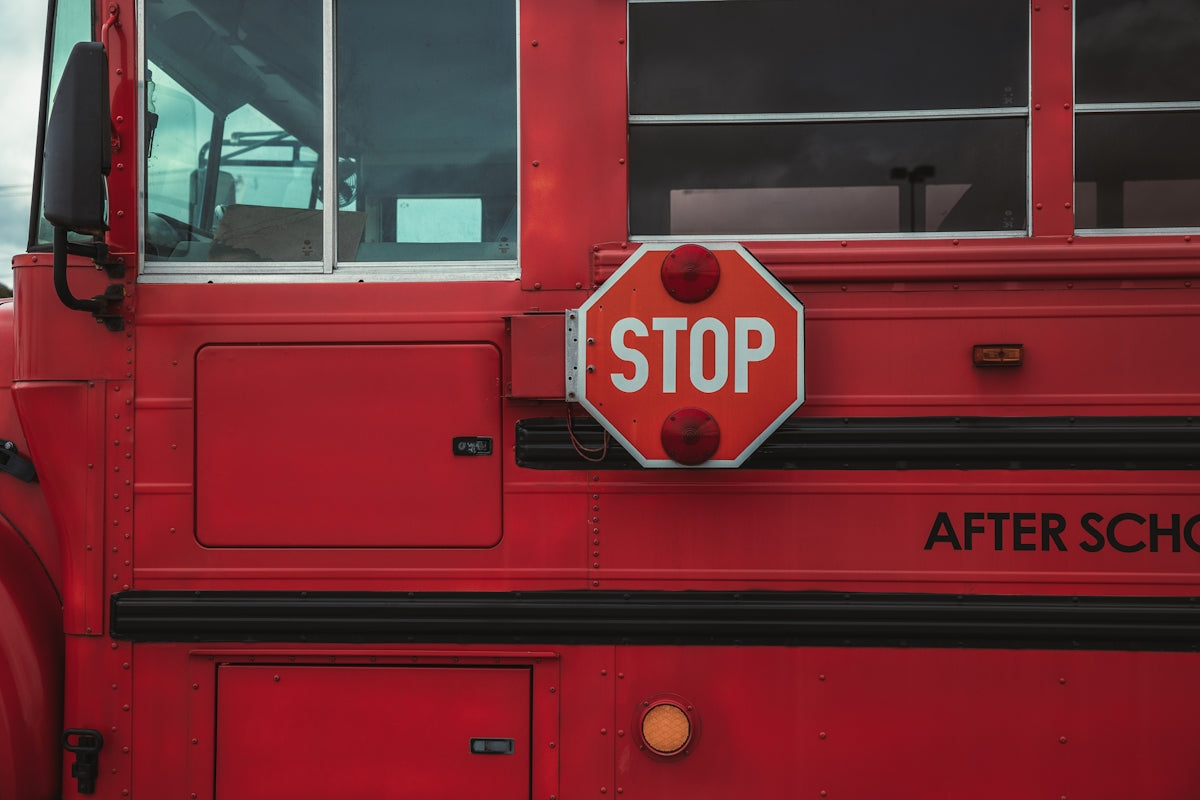 a red bus with a stop sign