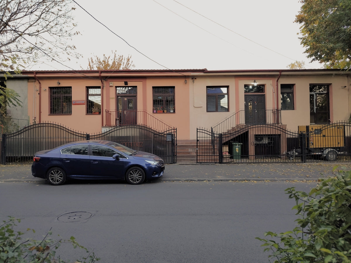 a blue car parked in front of a pink building