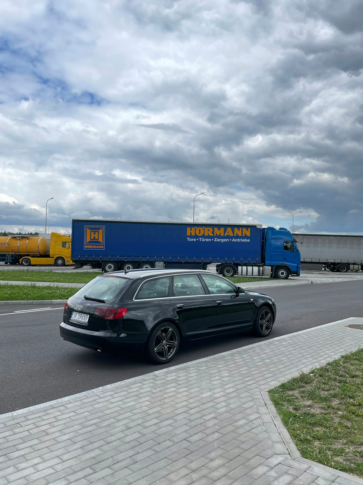 a black car driving down a street next to a blue truck