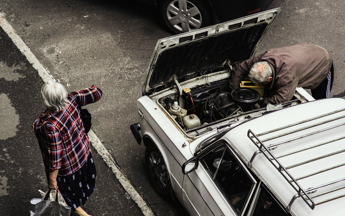 a man and a woman looking at a car with its hood open