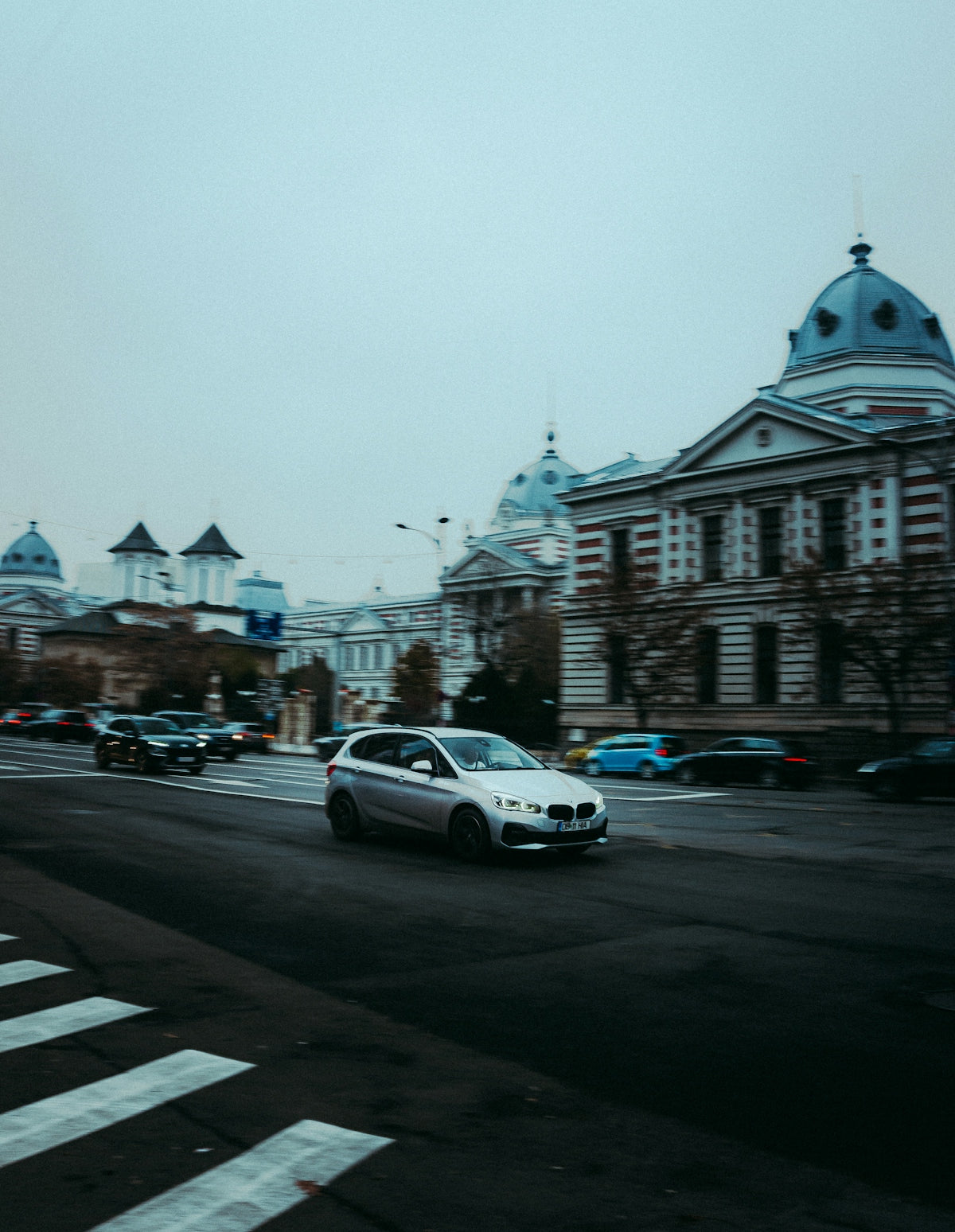 a white car driving down a street next to tall buildings