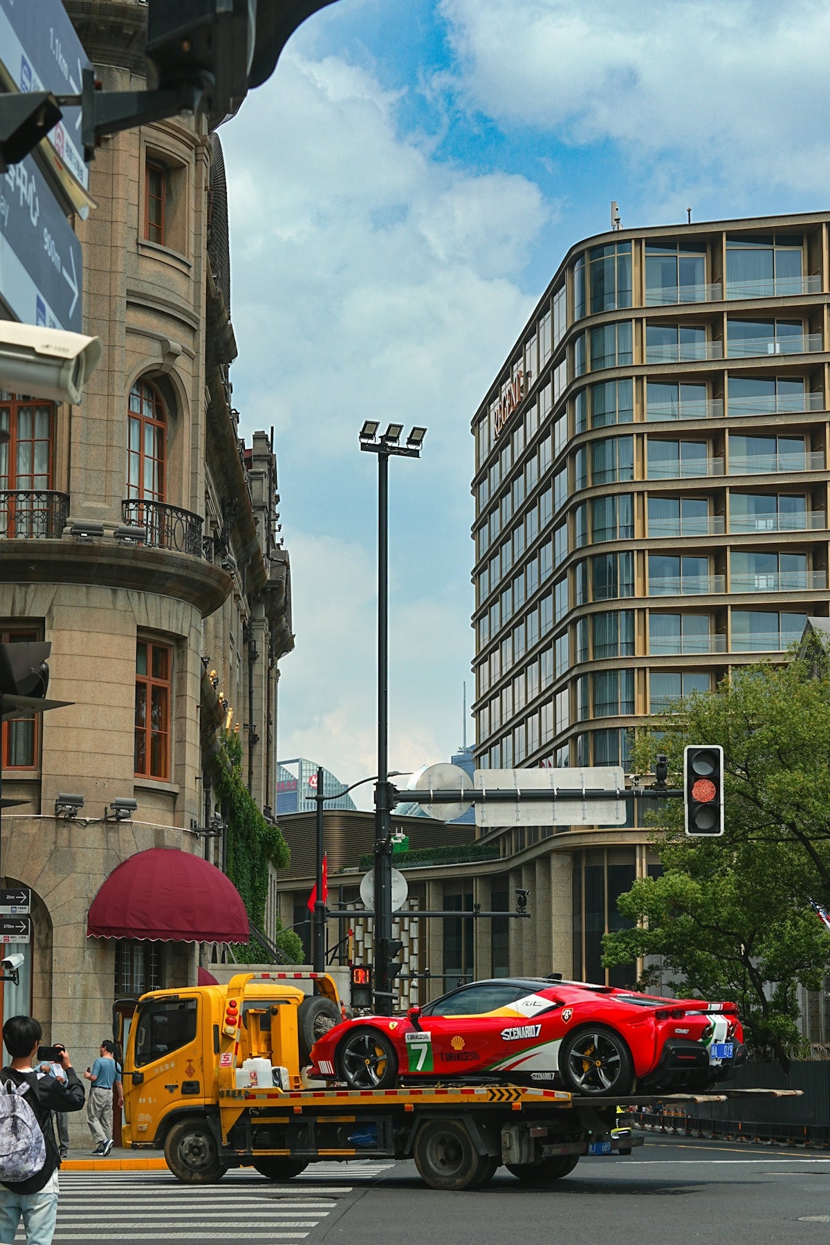 a tow truck towing a race car on a city street