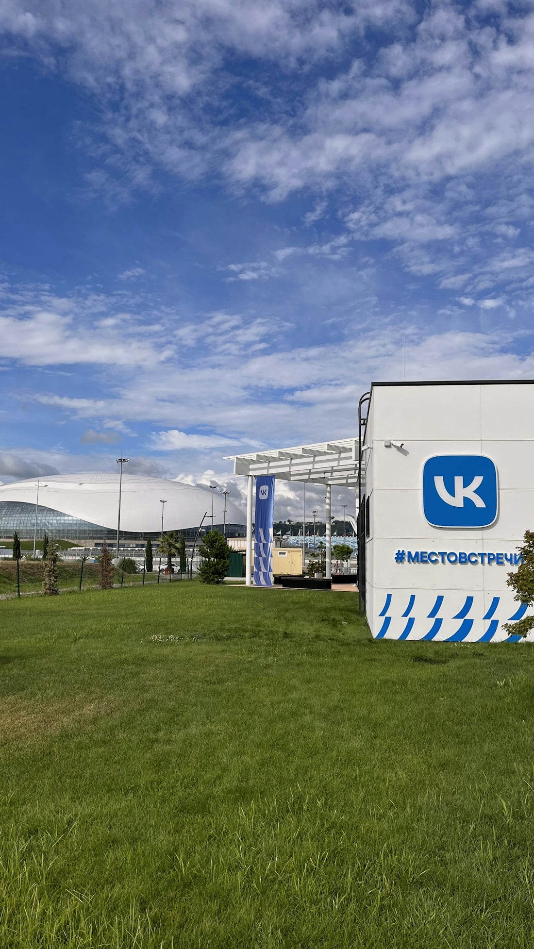 A large white sign sitting on the side of a lush green field
