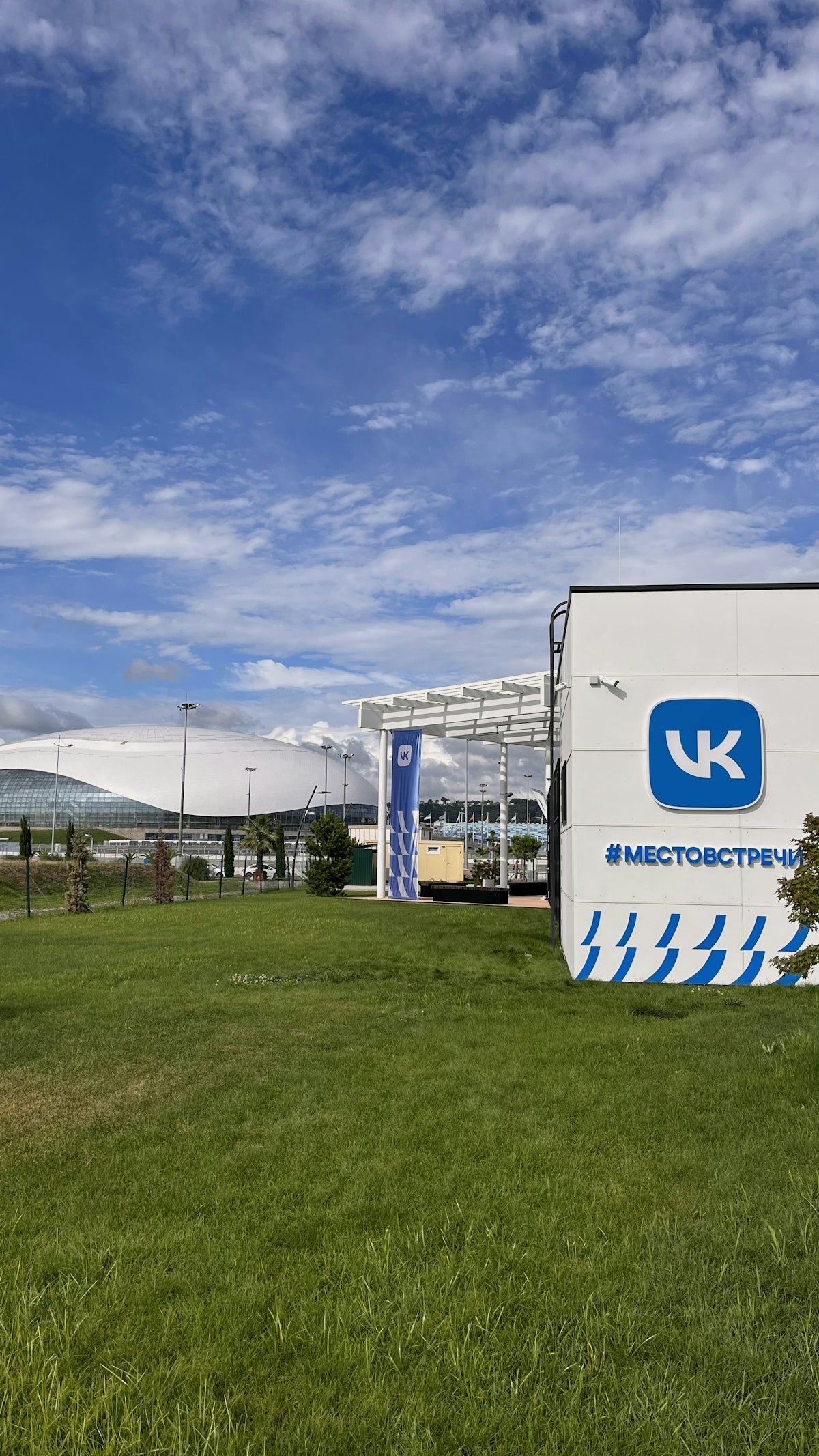 A large white sign sitting on the side of a lush green field
