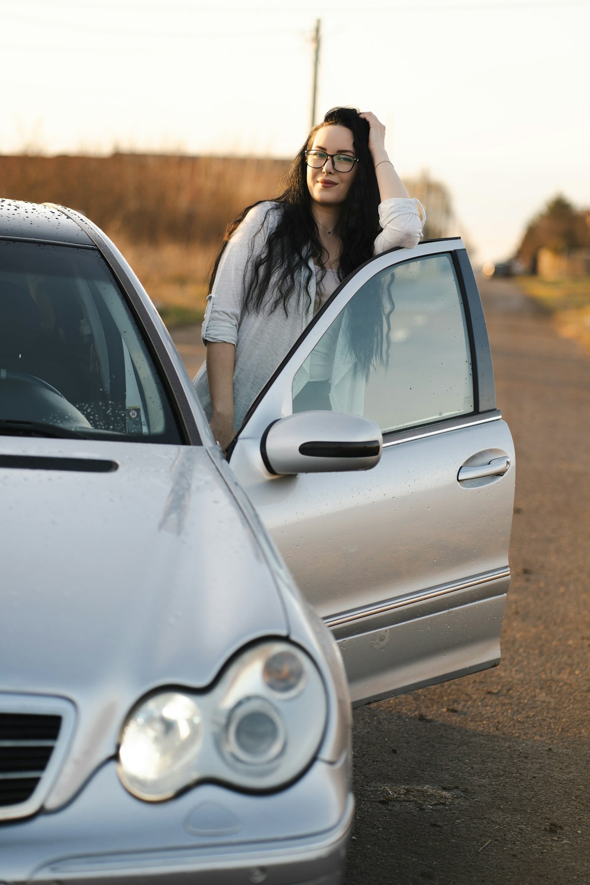 Woman poses by her car with an open door.