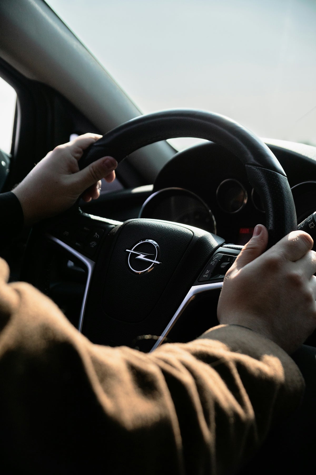 Hands grip an opel steering wheel, ready to drive.