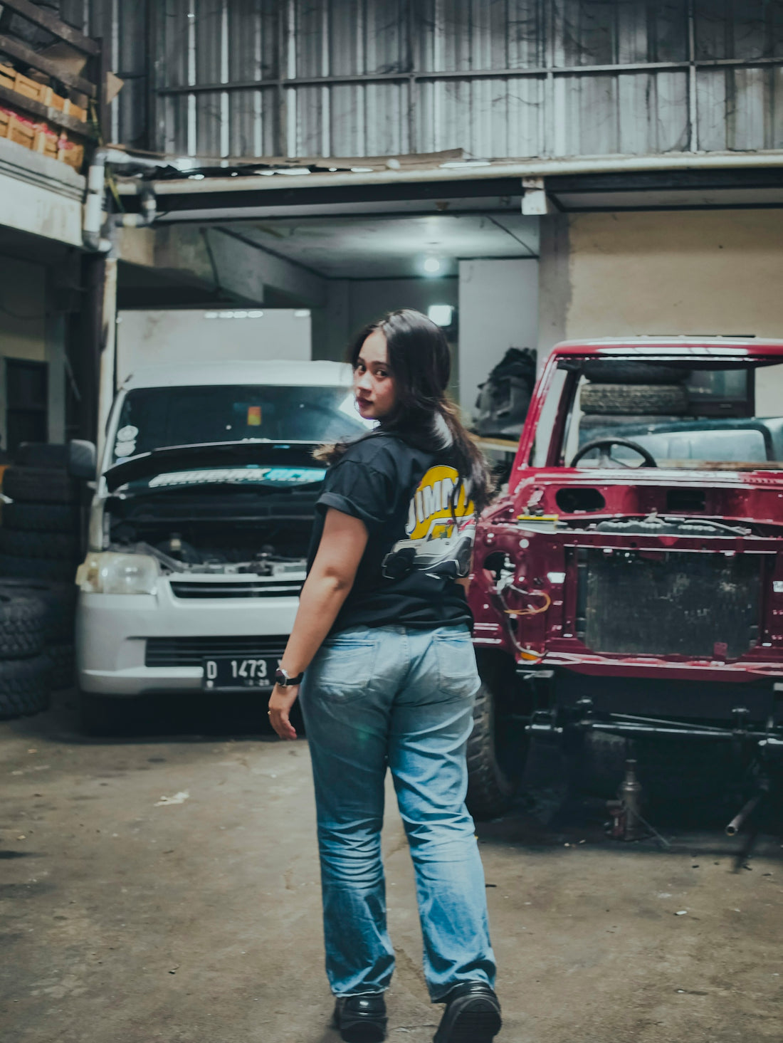 A woman stands in an auto repair garage.