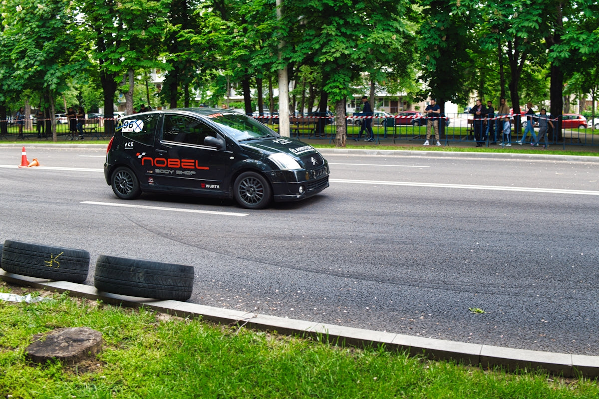 A small black car races on paved road.
