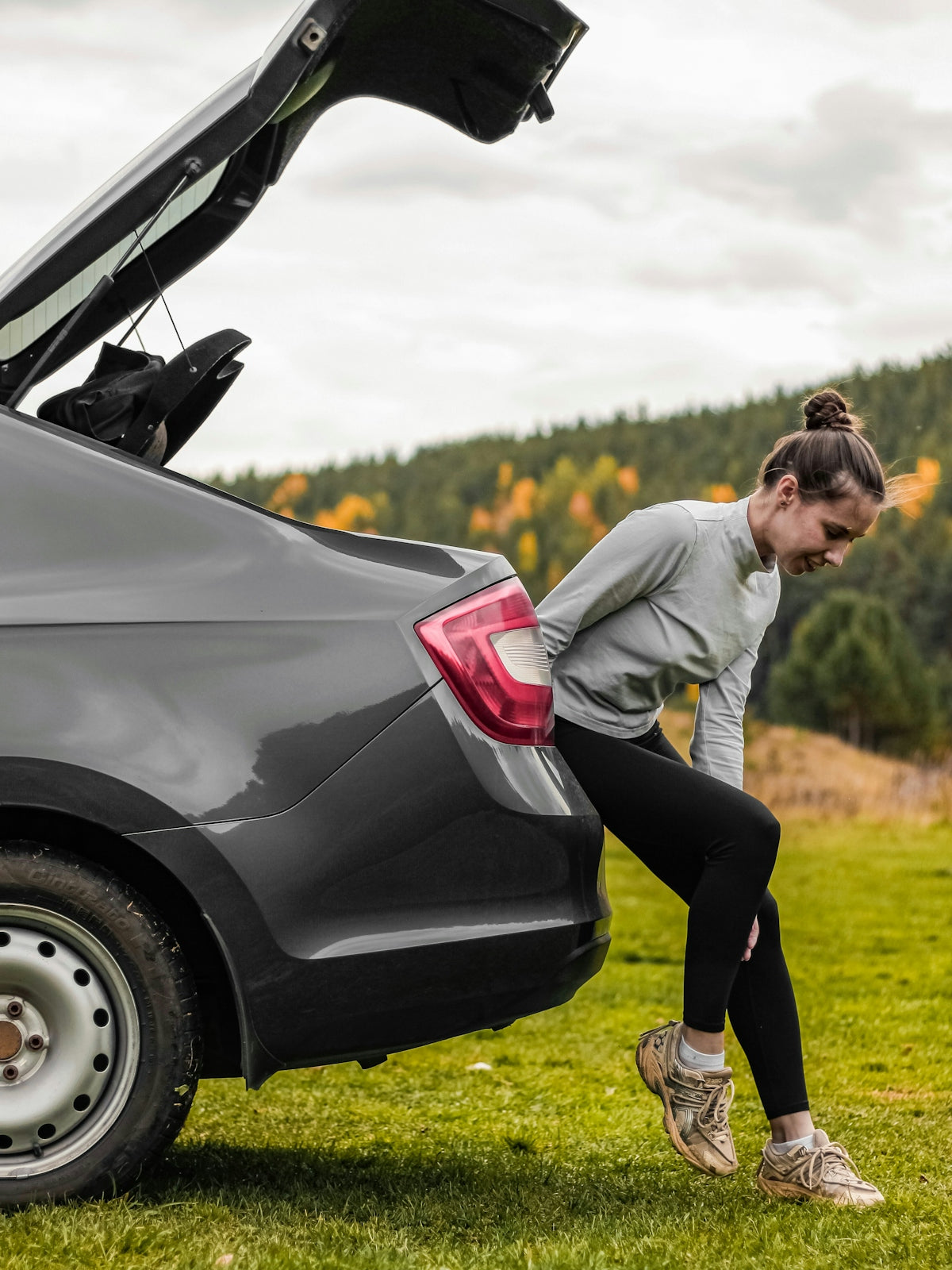 Woman loading luggage into car trunk outdoors.