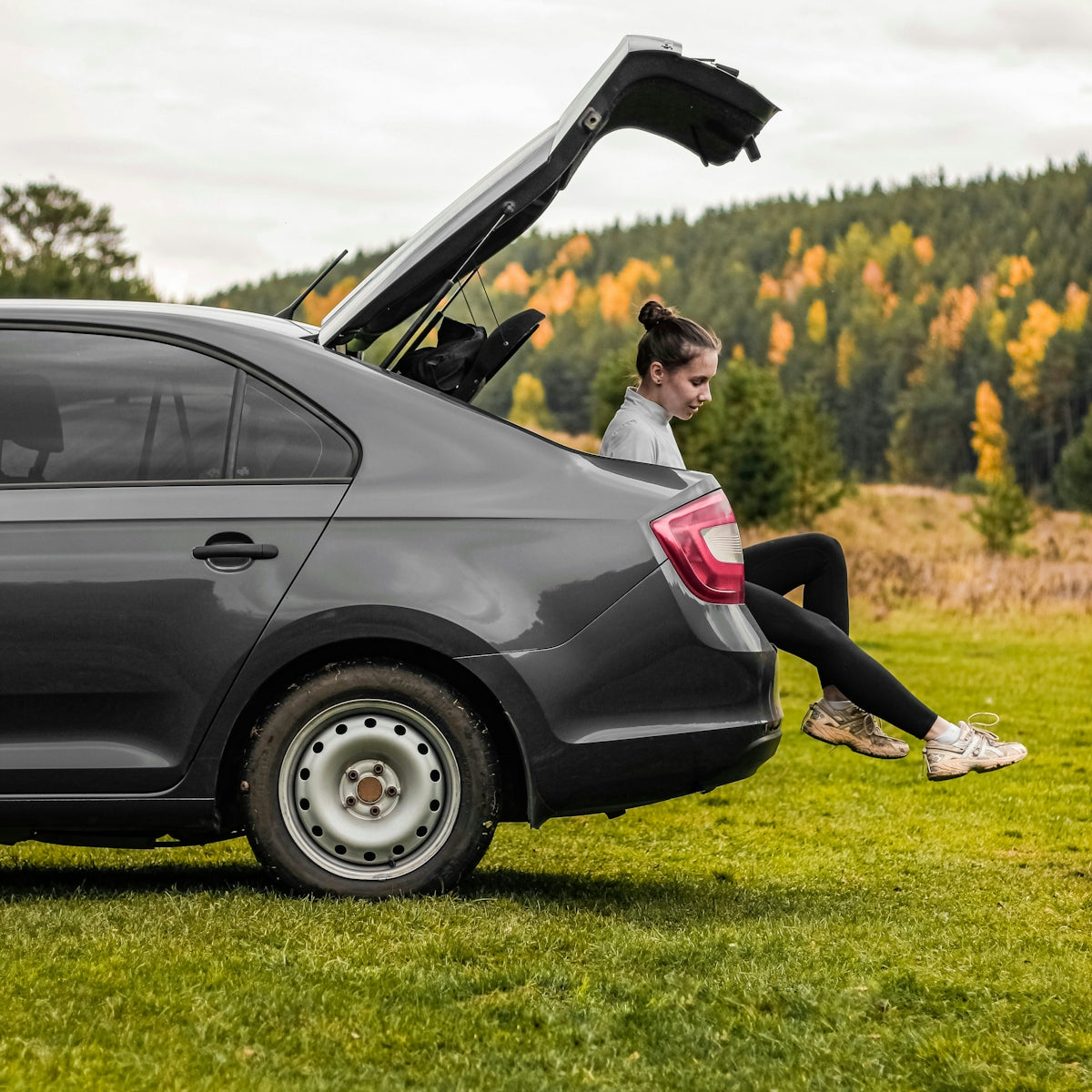 Woman sitting in the open trunk of a car