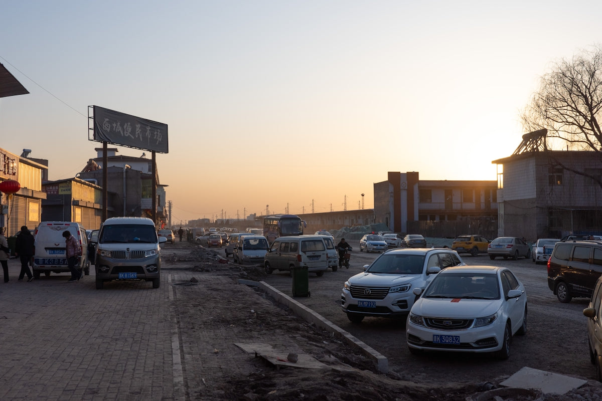 Cars parked on a dusty street at sunset