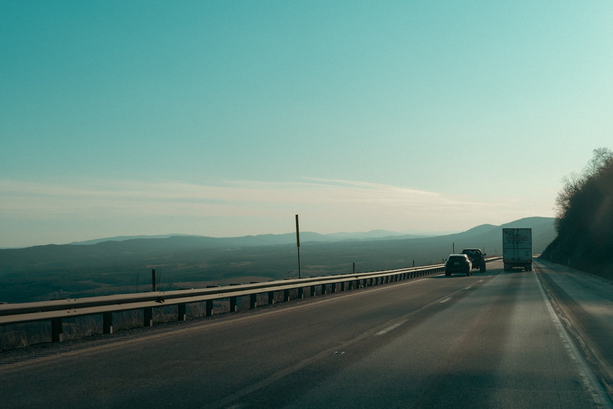 Trucks driving on a highway with distant hills.
