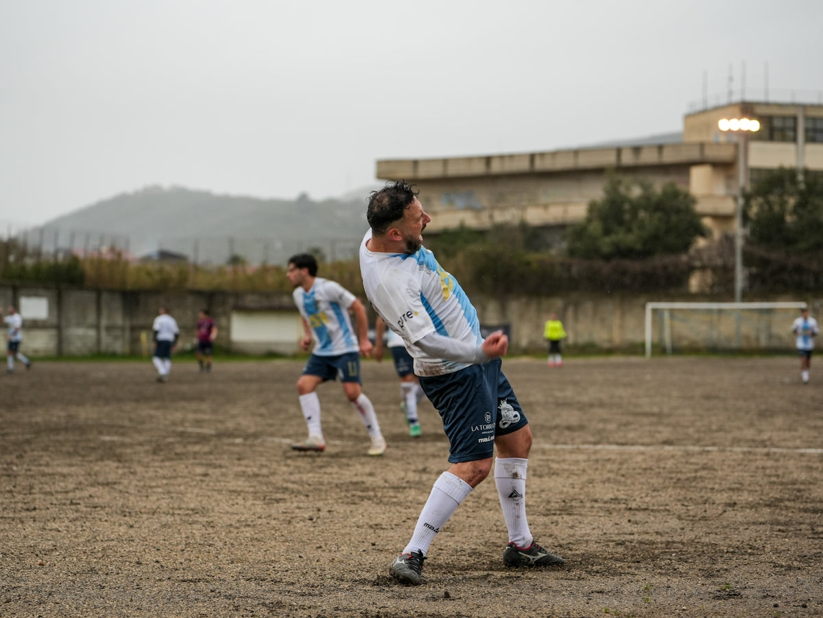 Soccer player celebrating a goal on a muddy field