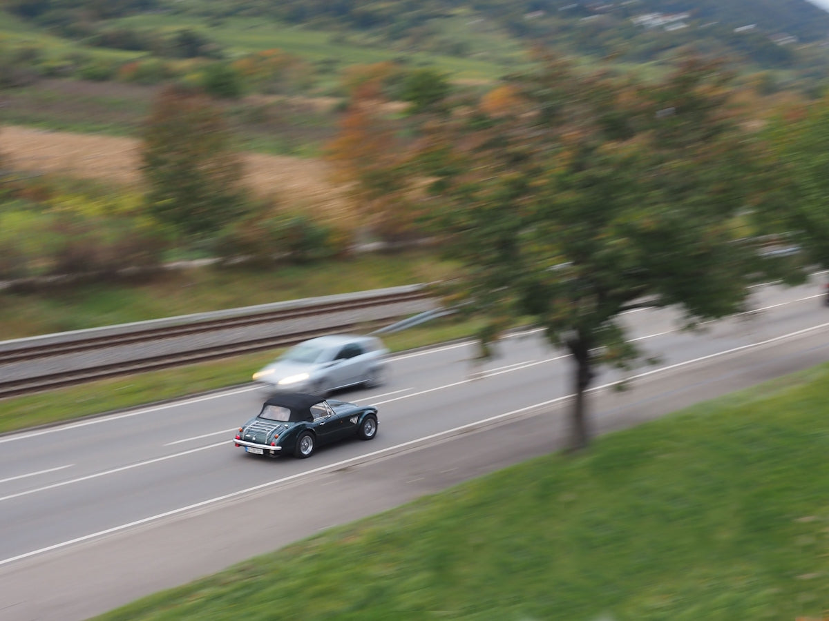 Two cars driving on a road with trees