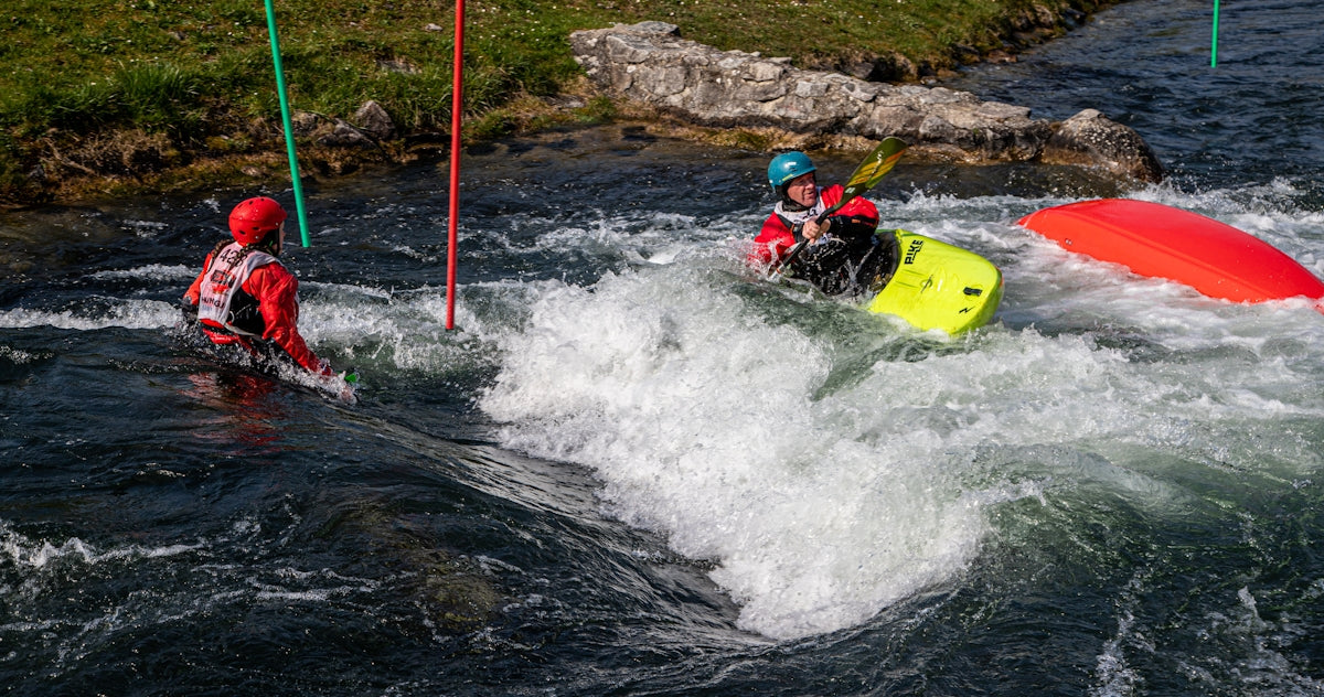 Kayakers navigate turbulent whitewater rapids with buoys.