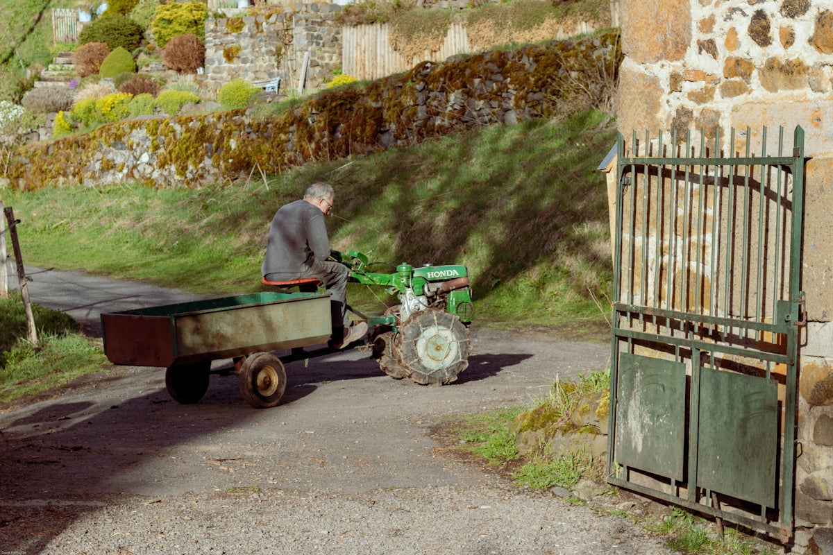 Man driving a small tractor with a trailer