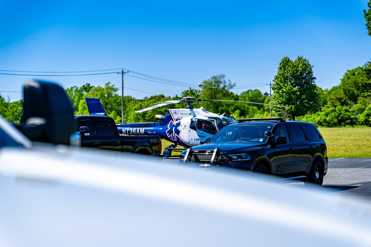 Emergency helicopter and vehicles under a clear blue sky.