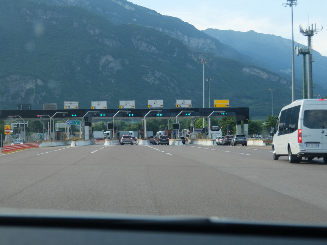 Cars approaching a multi-lane toll booth with mountains in background.