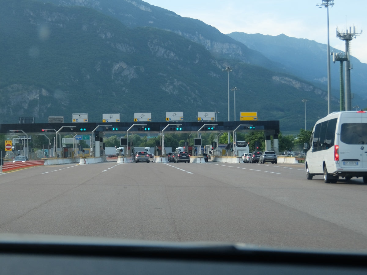 Cars approaching a multi-lane toll booth with mountains in background.