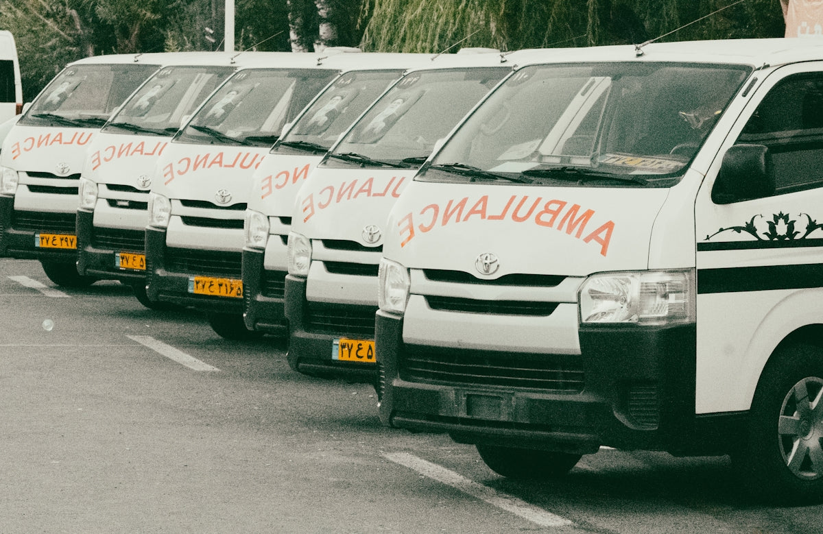 A line of white ambulances parked on a street.