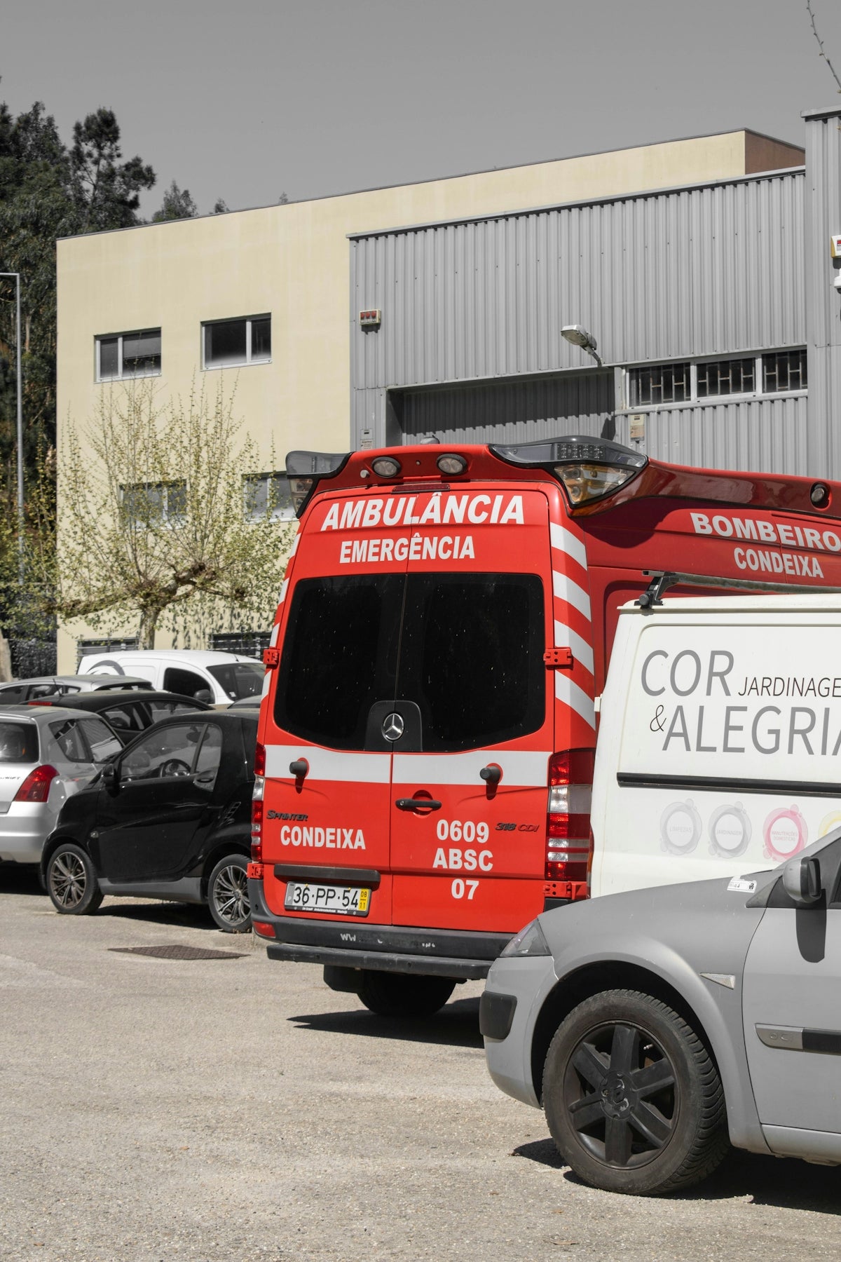 A red ambulance parked in a lot near a building.