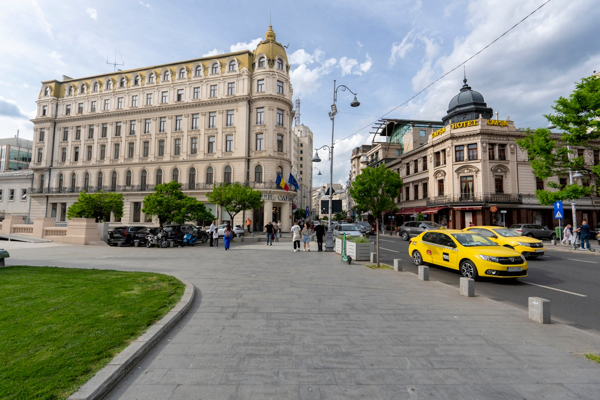 Elegant building, yellow taxis, and pedestrians on a city street.
