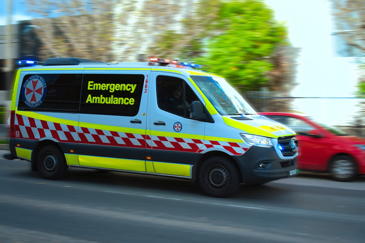 A New South Wales ambulance driving on a city street with motion blur